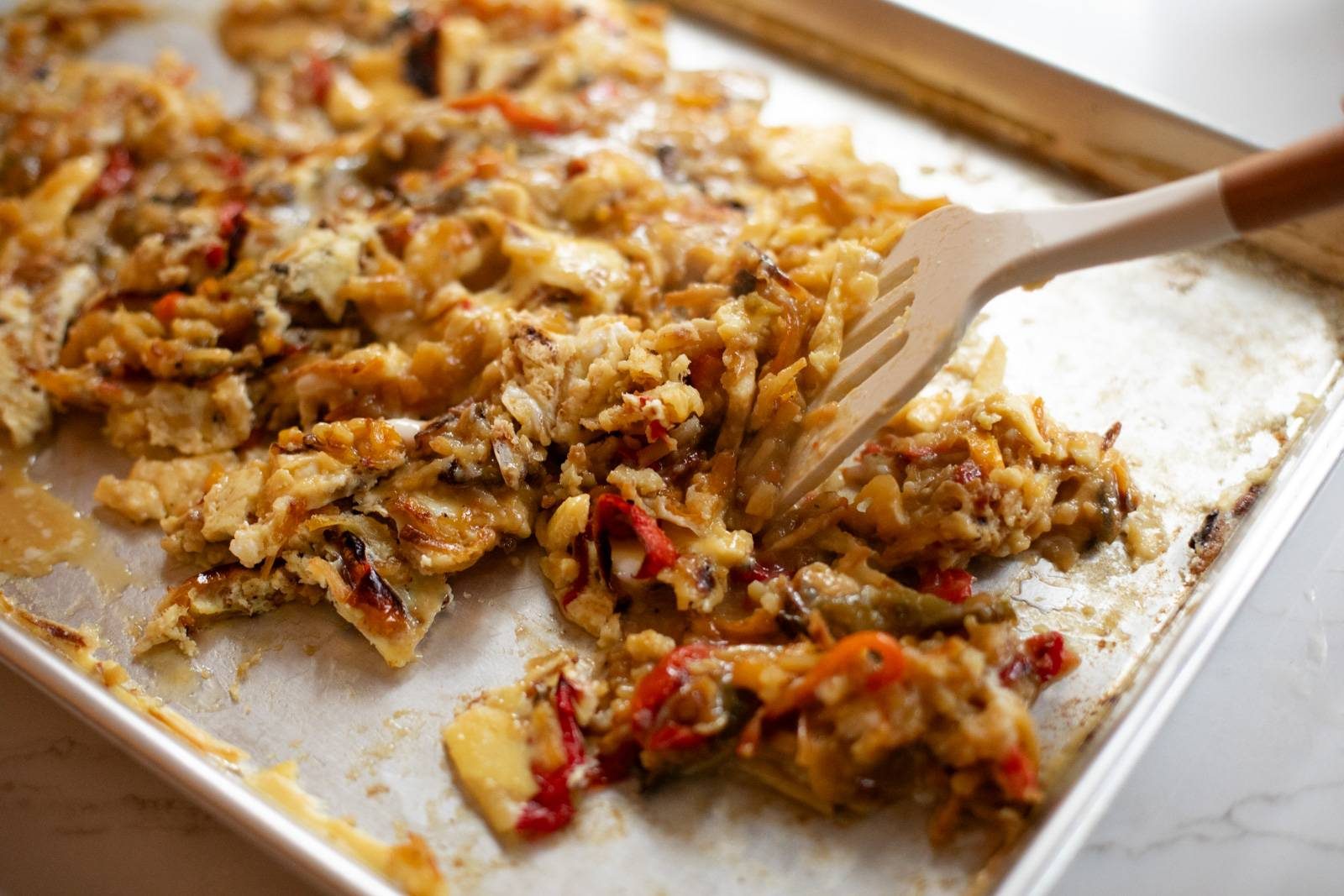 Pushing egg mixture around on a sheet pan.
